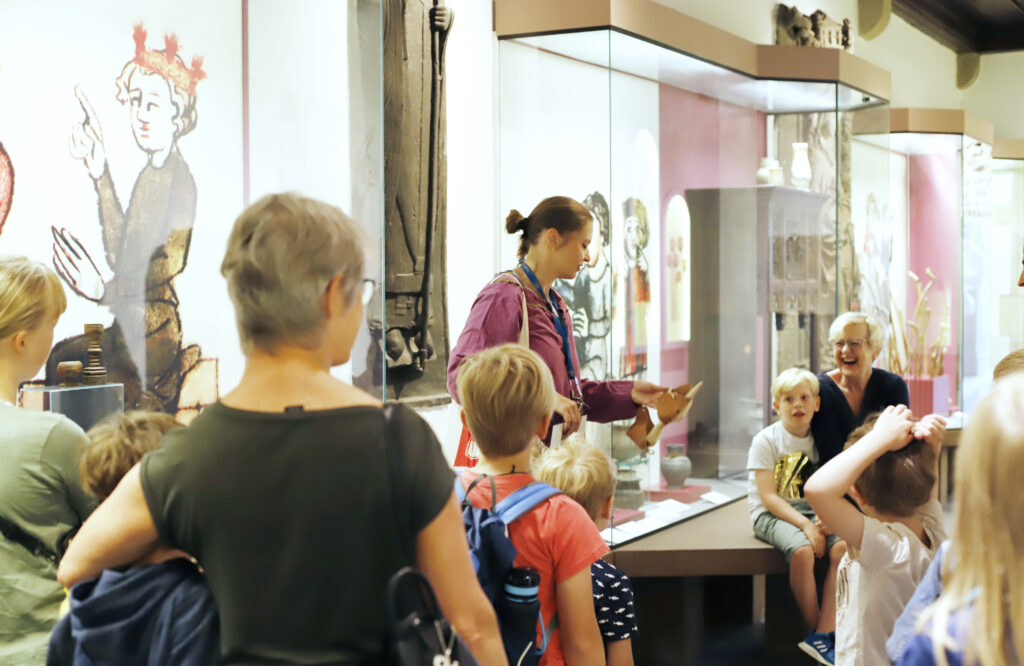 Auf dem Foto ist eine Pädagogin zu sehen, umringt von Kindern gibt Sie eine Führung